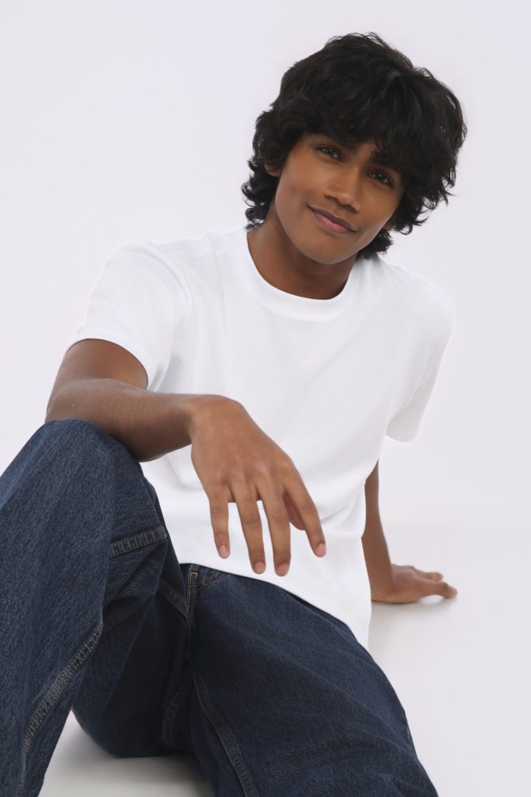 Shabs seated on the floor in a white tee and denim