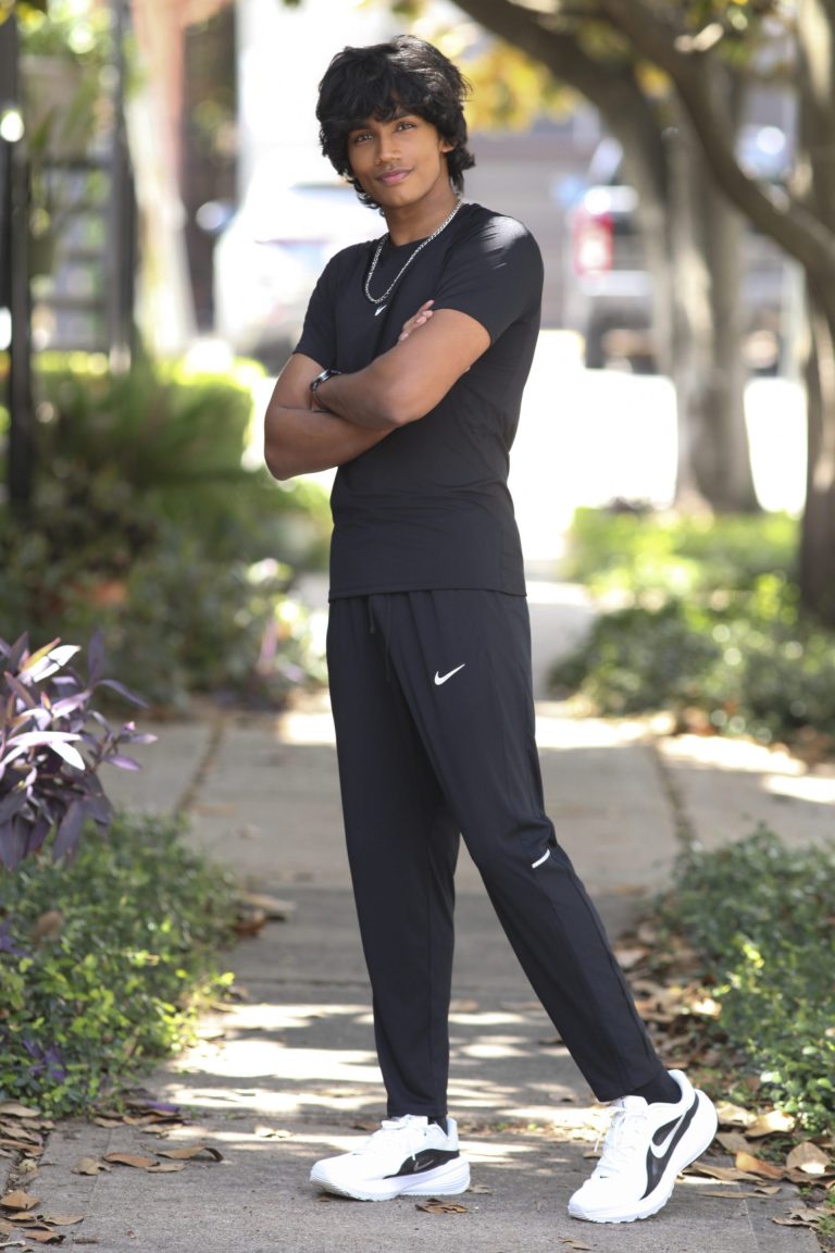 Shabs standing outdoors in black sportswear, arms folded